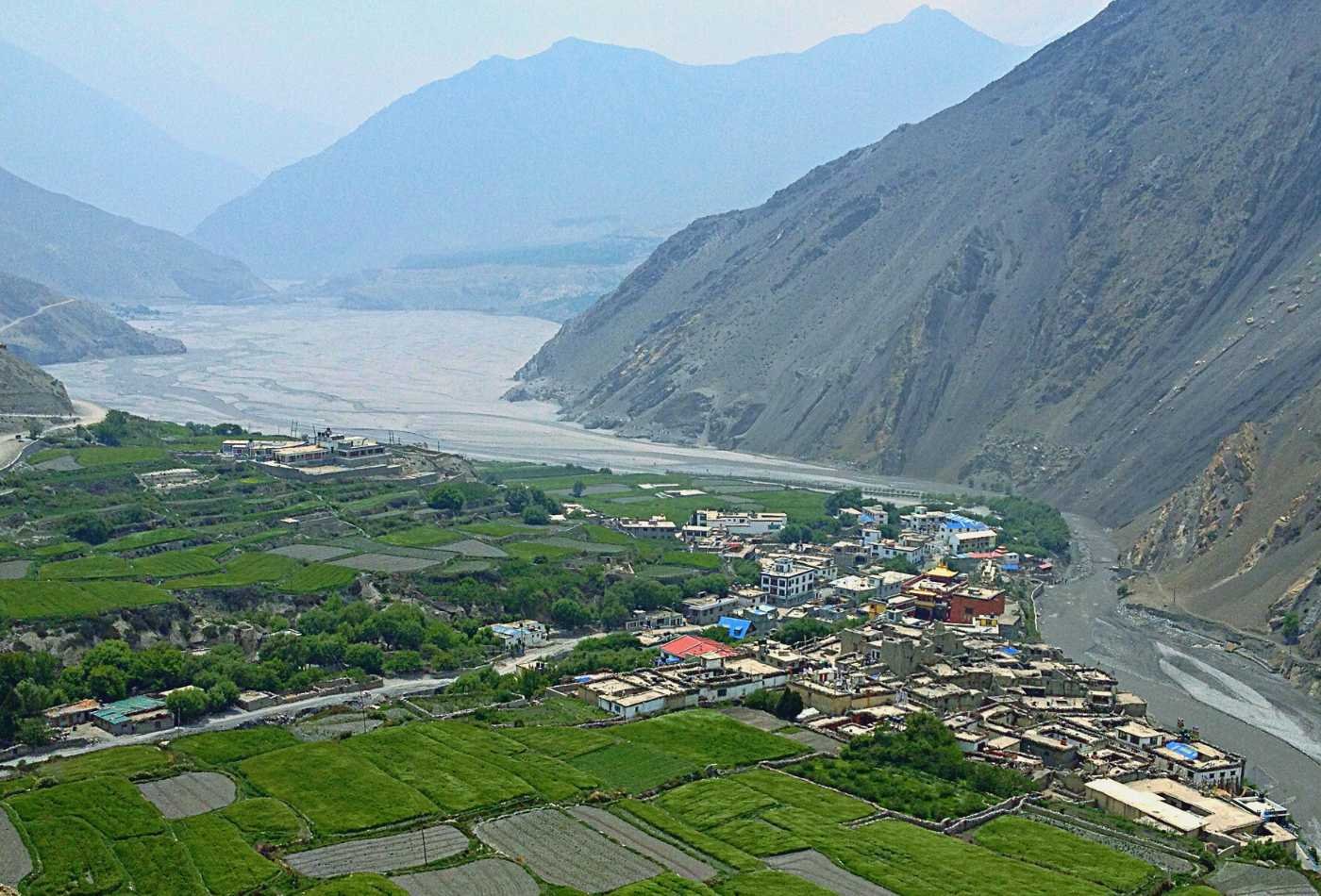 A charming view of Kagbeni village is nestled between the rugged mountains, surrounded by terraced fields and traditional mud-brick houses.