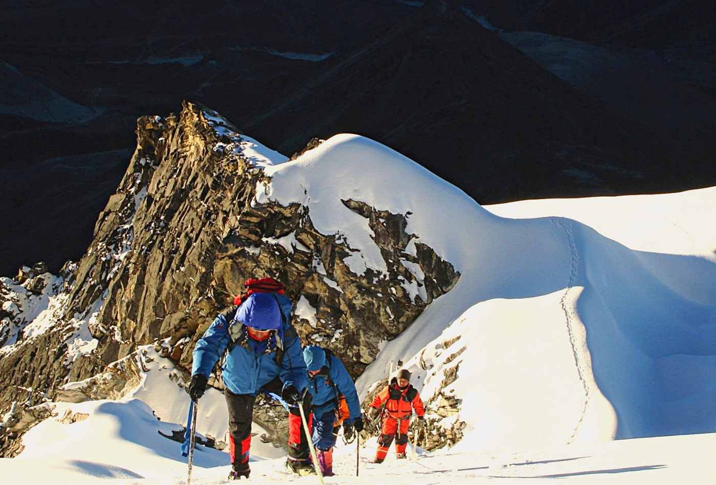 A group of determined climbers making their way up the steep slope of Labuche peak in the early morning light.