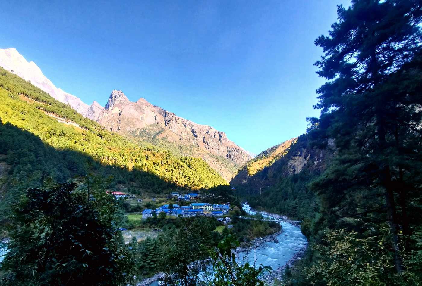 The village of Phikding bathed in the warm light of sunrise, with the Dudh Koshi river flowing by the side of the village.