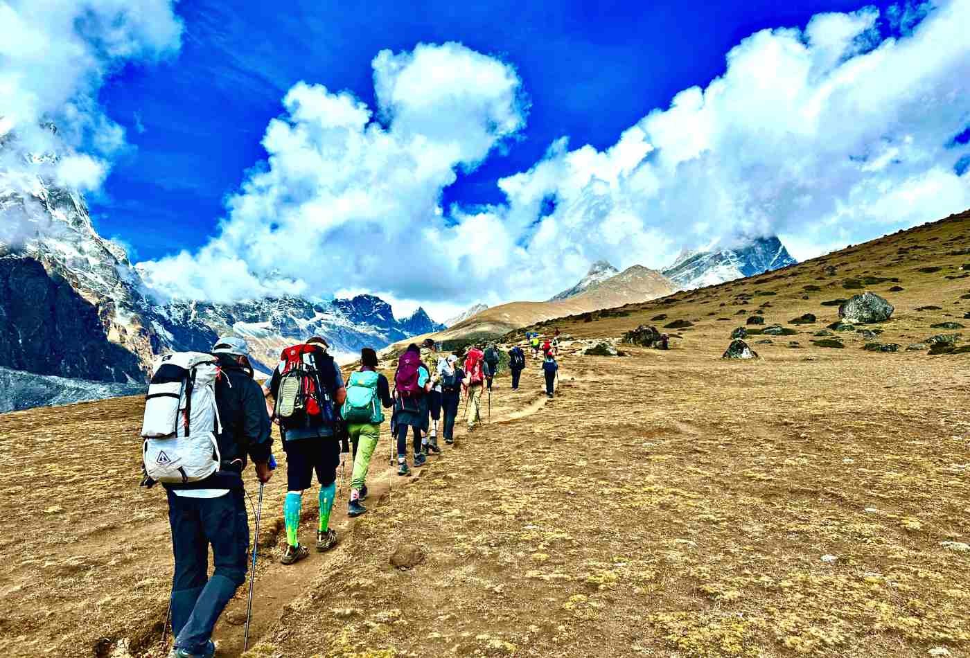 Group of trekkers standing in a queue, making their way to Mount Everest Base Camp, surrounded by the majestic Himalayan peaks.