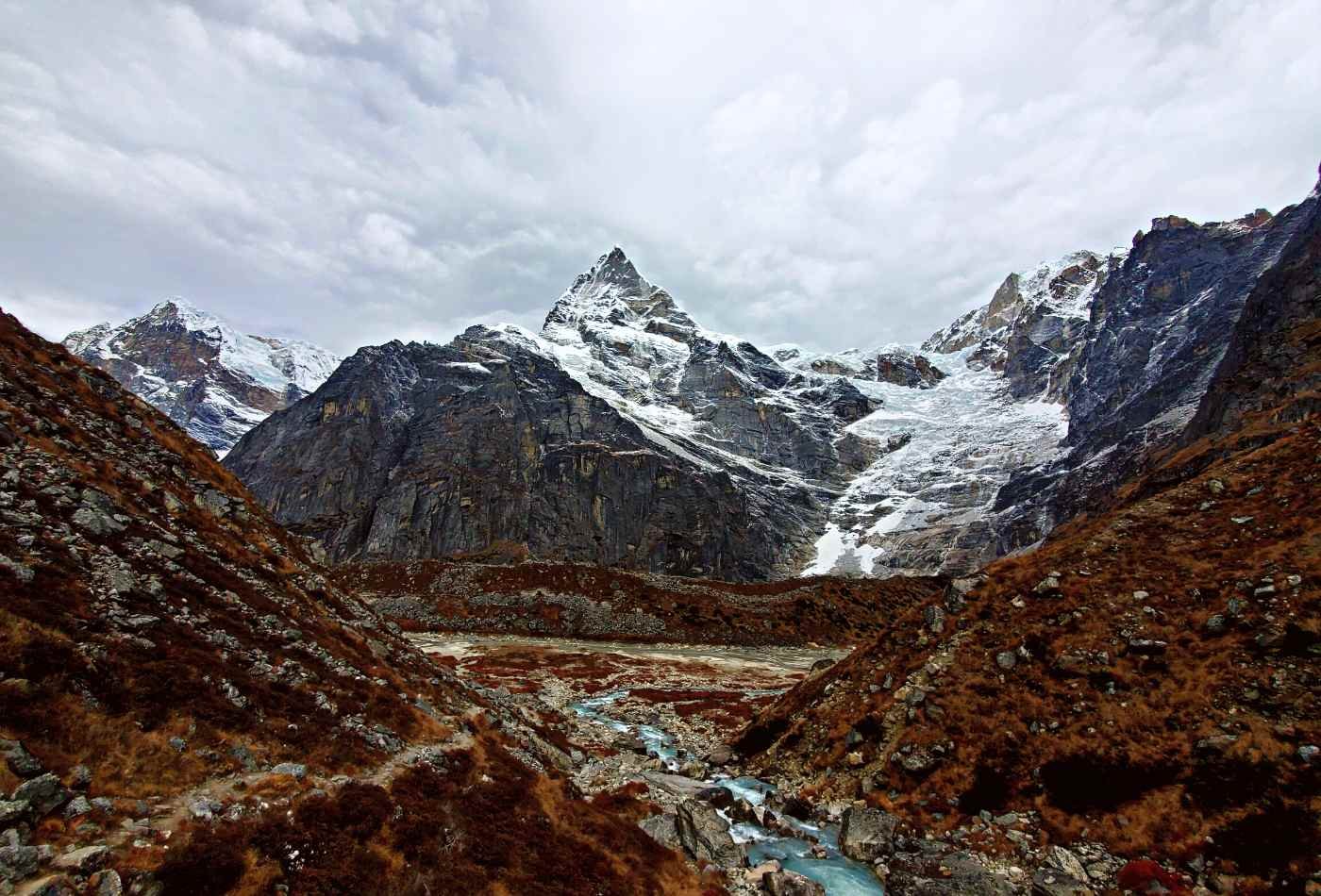 A beautiful view of Kyashar peak, with the majestic mountain towering in the foreground, and a small stream flowing in the surface.