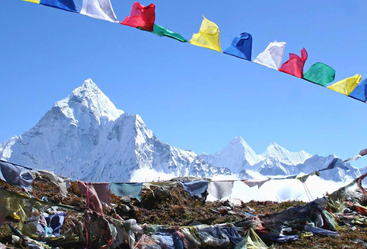 An awe-inspiring view of Mt. Amadablam, with its snow-covered summit, as seen from Thukla with colorful prayer flags fluttering in the wind. 