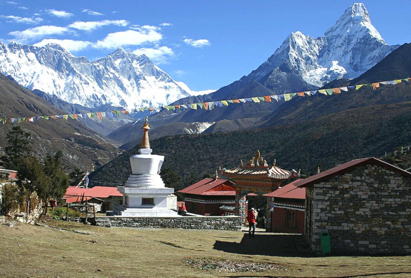 A panoramic view of Mt. Amadablam, Mt. Lhotse, and Mt. Everest as seen from Tengboche Monastery, with a traditional stupa in the foreground.