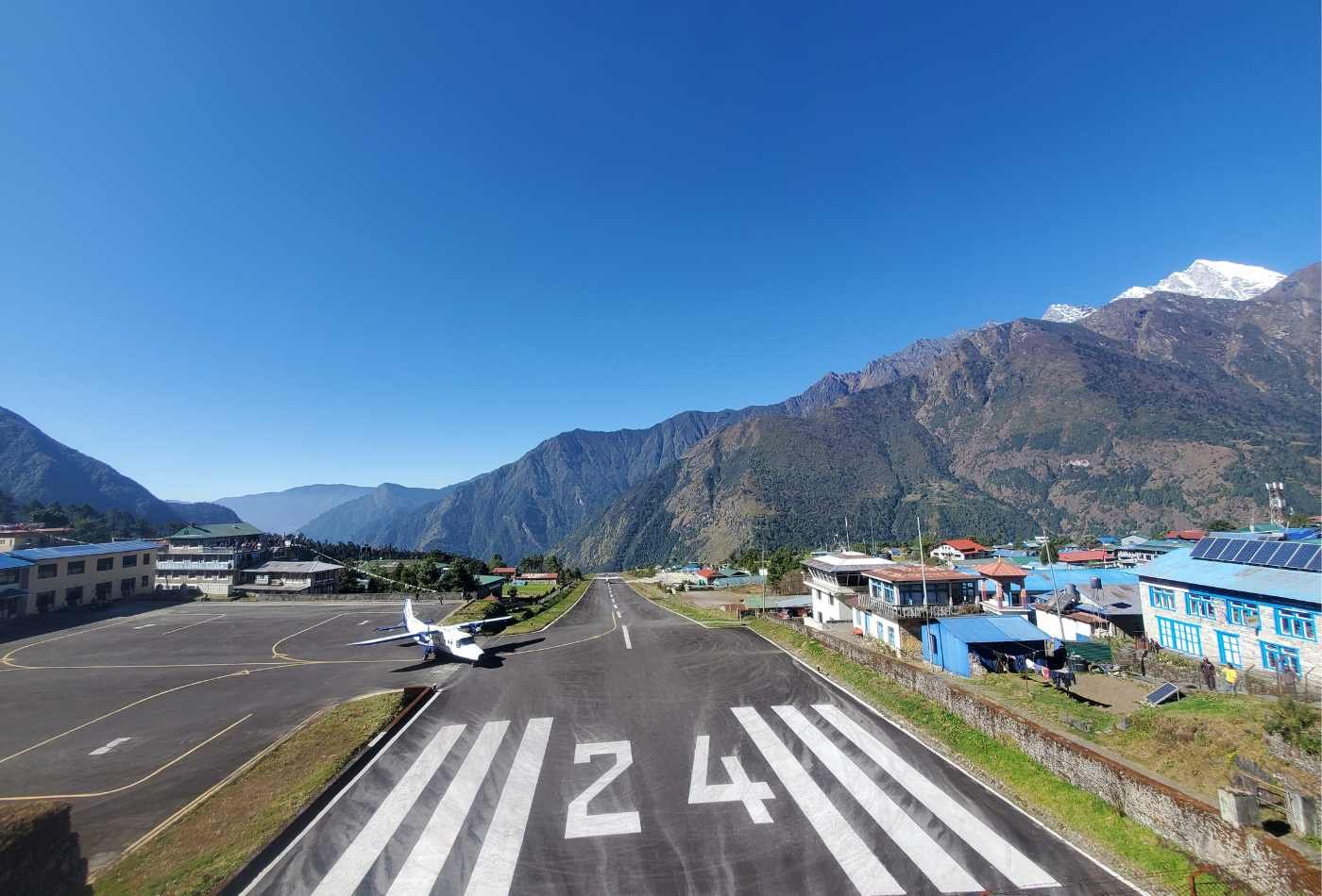Lukla Airport, a small mountain airport with an airplane ready for take-off on a clear day, providing access to the trekking routes to Mount Everest.