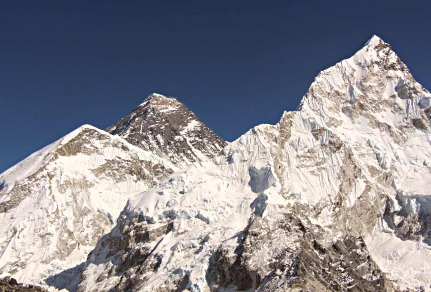 A stunning view of Mt. Everest and Nuptse peak is seen from Kalapatthar. The snow-covered mountain peaks rise high into the sky.