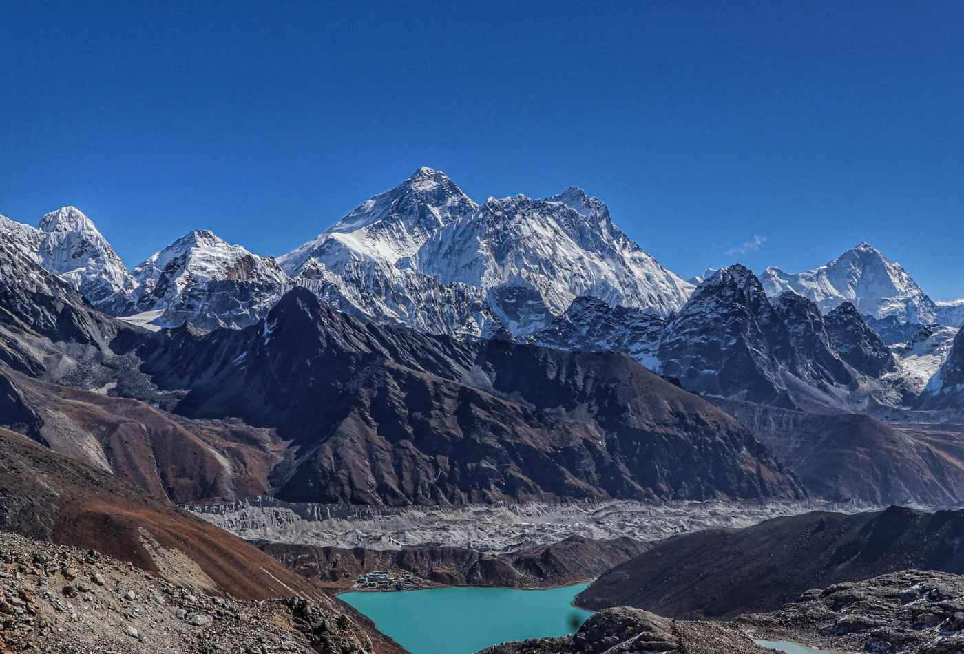 A breathtaking view of Mt. Everest and the surrounding mountain peaks, as seen from Ranjo La Pass. The snow-capped peaks rise above the clouds.