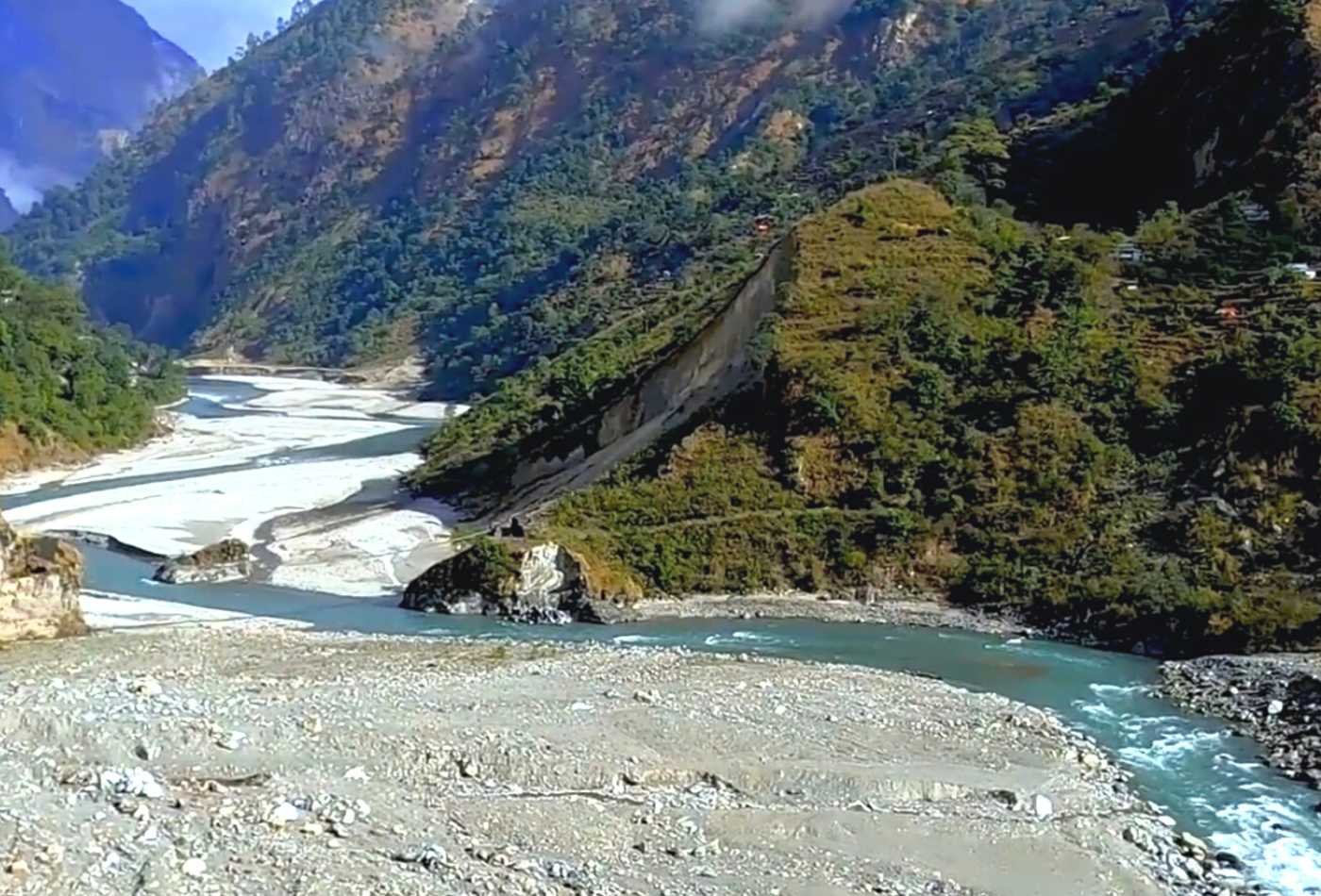 A scene of the Budi Gandaki river during the Manaslu Circuit Trek. The crystal-clear water flows peacefully through a lush green landscape. 