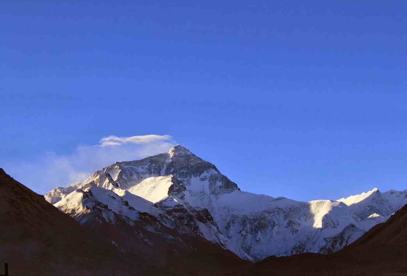 Mt. Everest, the highest peak in the world, stands tall and majestic in the clear blue sky as viewed from the Tibetan side.