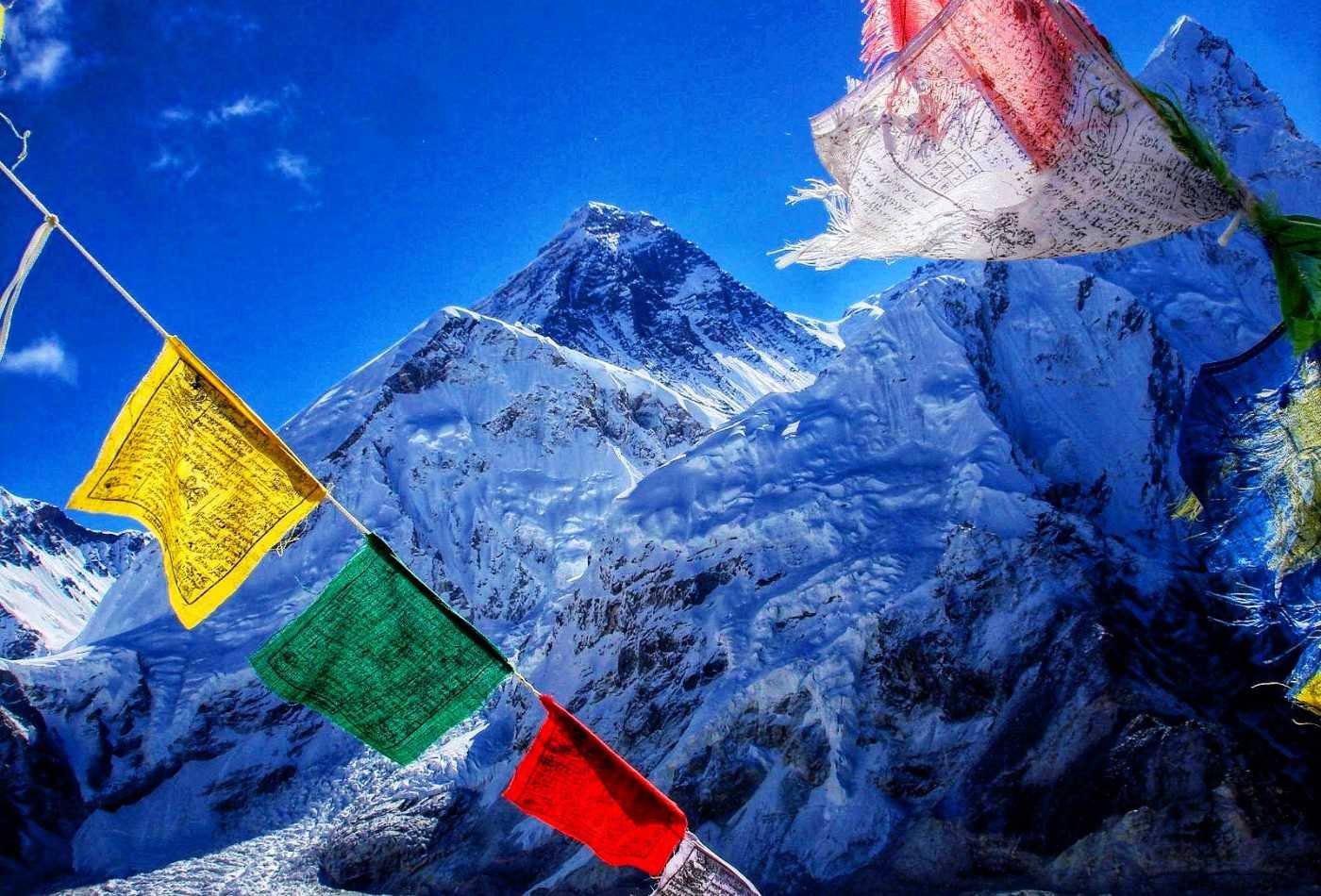 View of Mount Everest from Kalapatthar viewpoint, with prayer flags fluttering in the wind in the foreground.