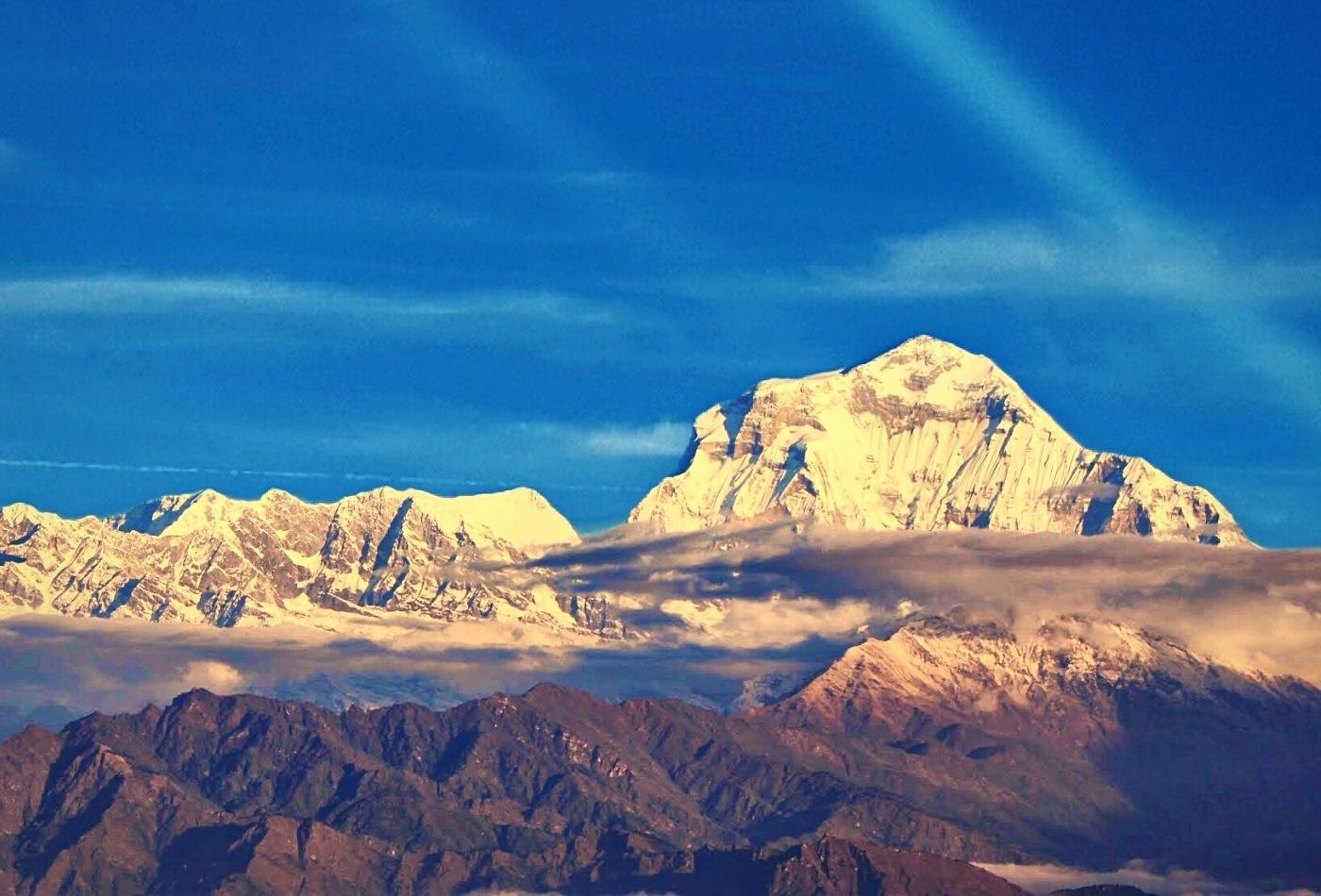 A beautiful sunrise view of the majestic Mt. Dhaulagiri, with scattered clouds adding to the natural beauty of the scene from Poon Hill.