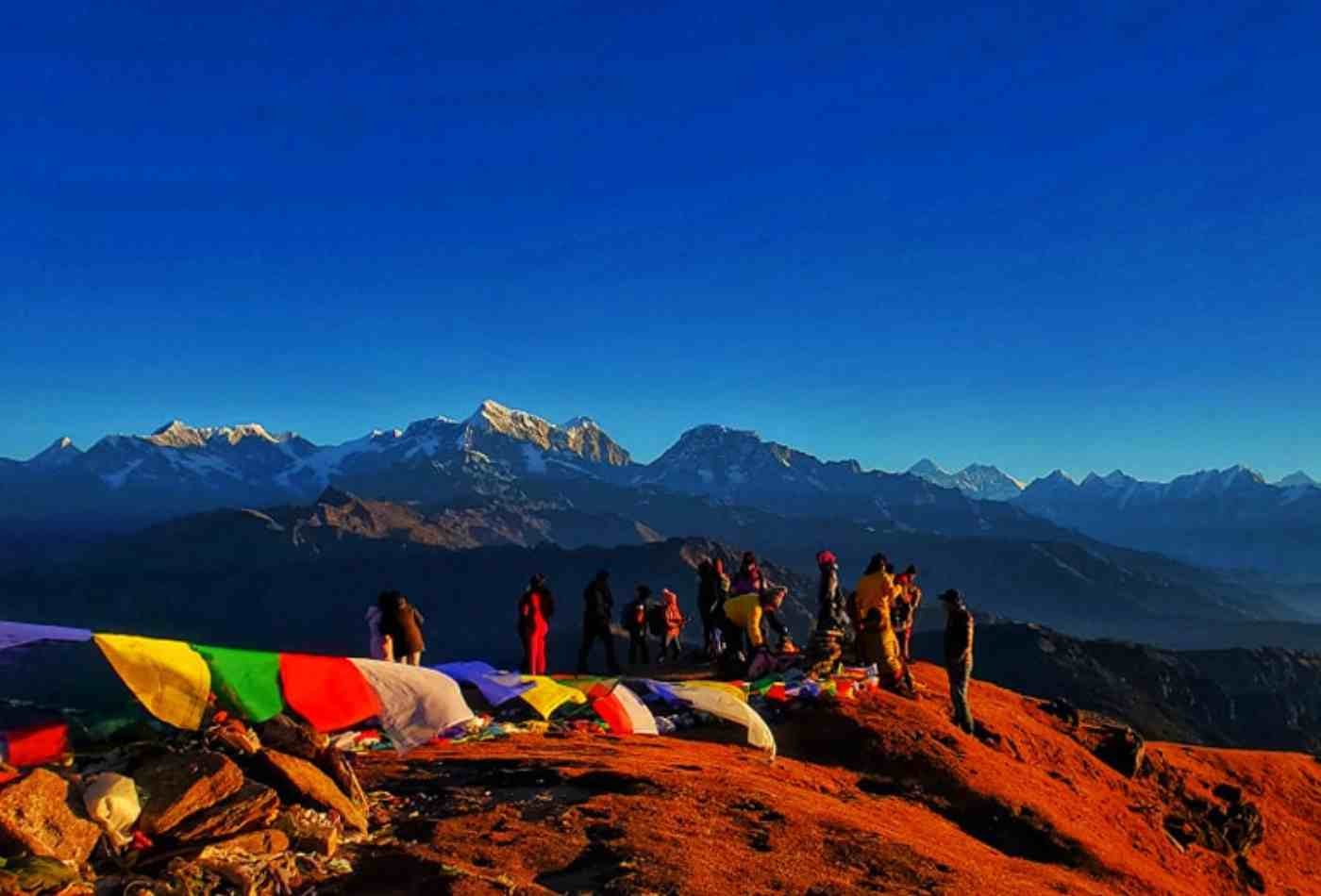 A breathtaking view of Pikey Peak at sunrise, surrounded by majestic mountains and with the distant peak of Mount Everest visible on the horizon.
