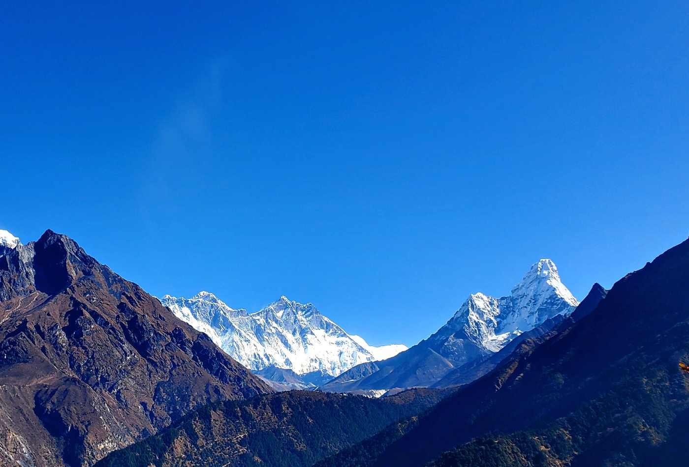  A stunning view of Cholatse Peak from Dzongla, with clear blue skies and snowy peaks. The rocky terrain and green grass in the forehand. 
