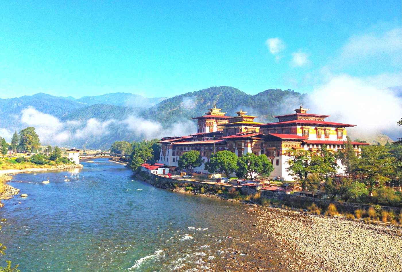 A picturesque view of Punakha Dzong, an ancient fortress and Buddhist monastery in Bhutan with clouds in background. 