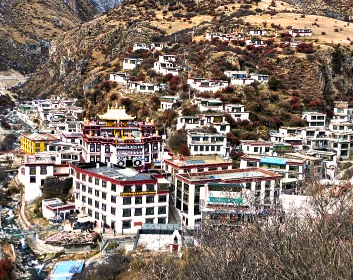 Tidrum Nunnery, a red and white Tibetan Buddhist nunnery located in a gorge with a river running alongside it.