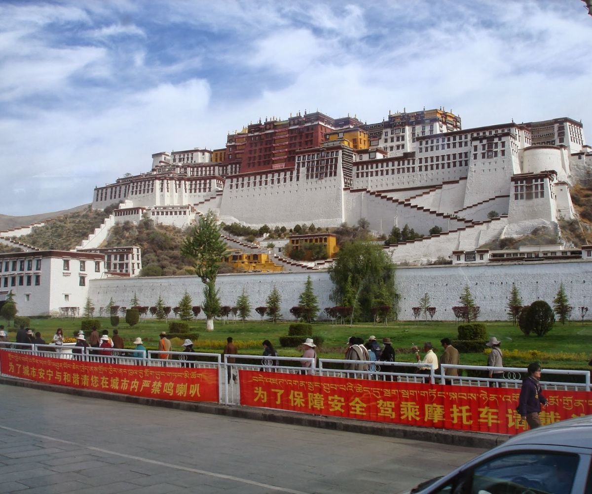 The Potala Palace in Lhasa, Tibet, with its distinctive white and red color scheme and a clear blue sky in the background.