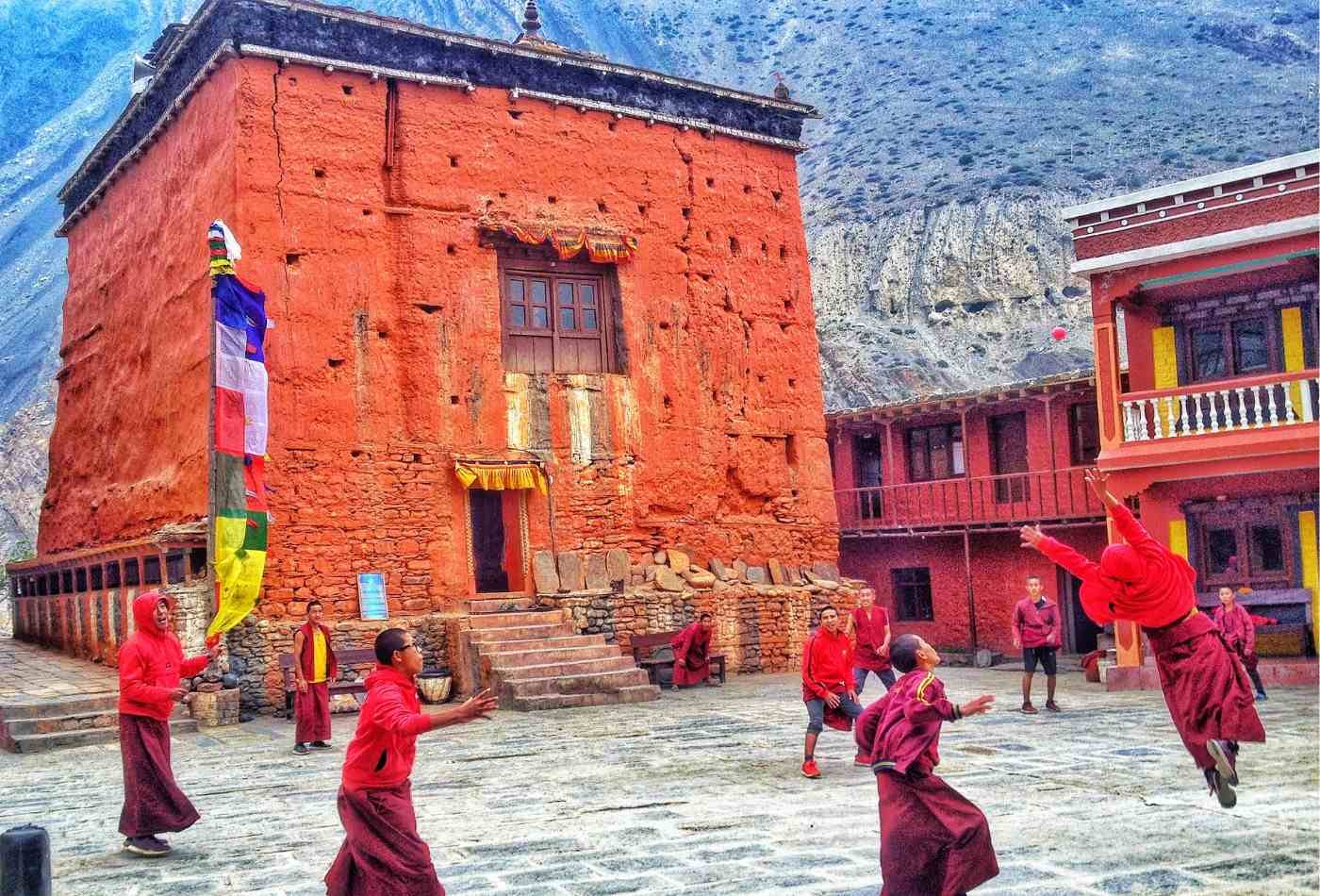 Monks playing a ball game in front of a red-walled monastery in Kagbeni, Nepal.