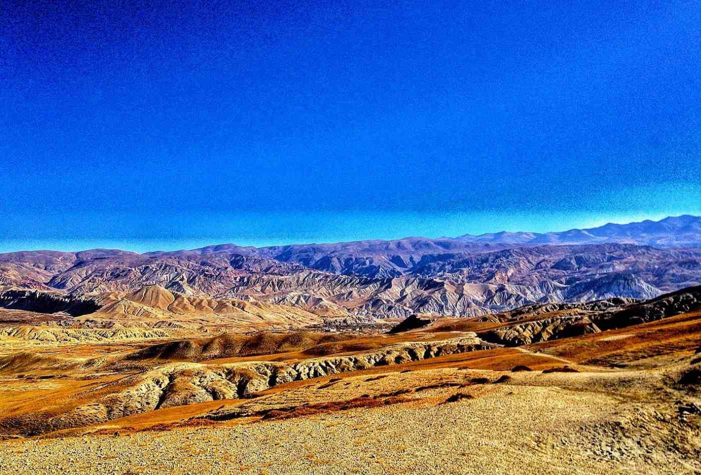 A breathtaking landscape view of the Upper Mustang region with clear skies and an abundance of rolling hills.