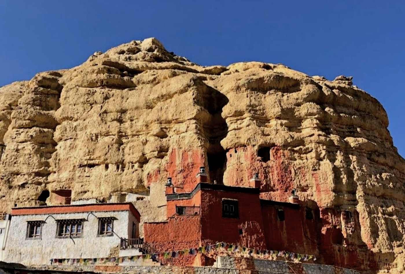 A vibrant red and white painted monastery nestled amidst the hills in the Chossar Village in the Upper Mustang region.
