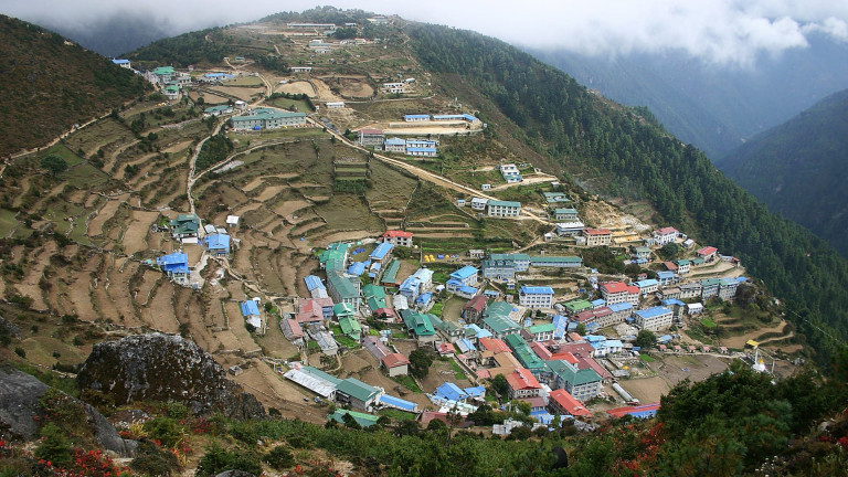 Namche Bazzar, a mountain village and trading center in the Solu-Khumbu region of Nepal with colourful roofs and green forest.